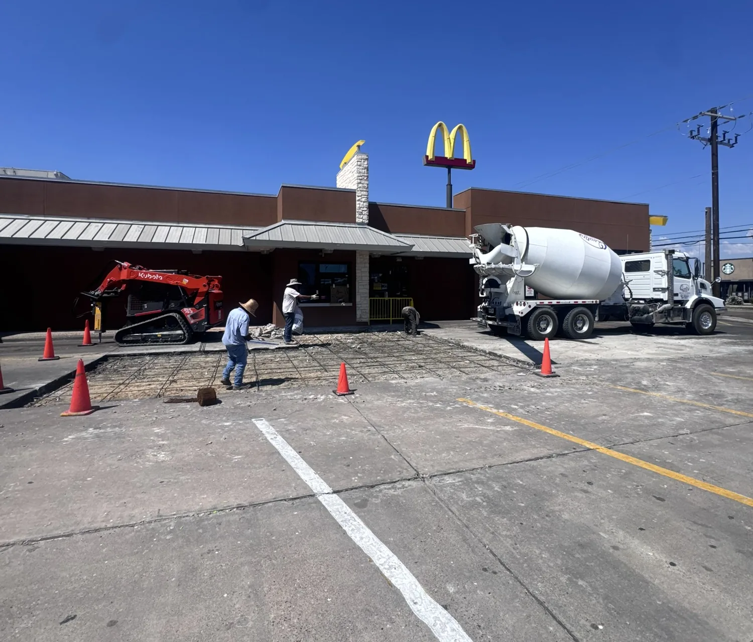 Lucky's Concrete crew pouring a commercial parking lot at a McDonald's with wire mesh and a concrete mixer truck on site